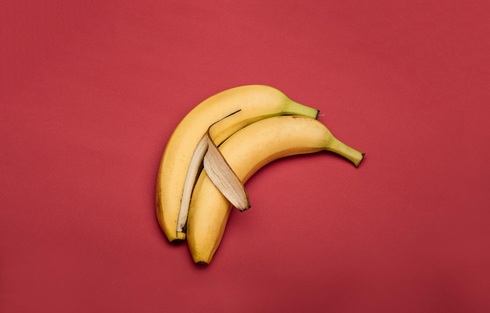 Creative arrangement of bananas on a vibrant red background.