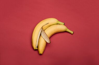 Creative arrangement of bananas on a vibrant red background.
