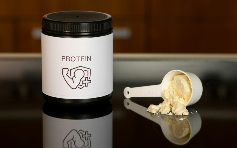 a container of protein powder next to a spoon