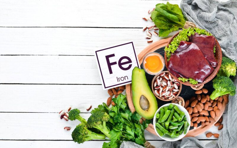 Jak niedobór żelaza u sportowców wpływa na wydolność fizyczną? 6 food containing natural iron fe liver avocado broccoli spinach parsley beans nuts white wooden background top view wp